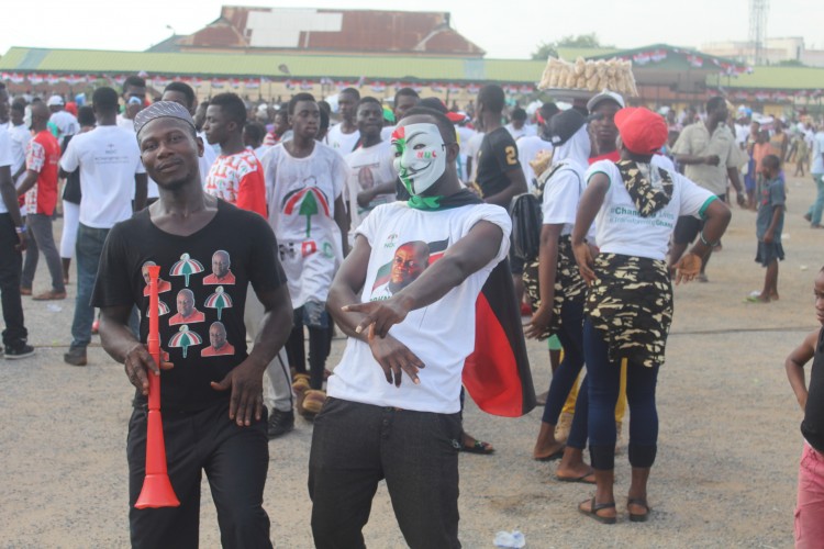 Two people pose in NDC-affiliated clothing at a campaign rally.